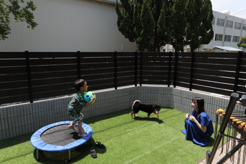 インナーガレージのある子育て家族の住まいの施工例。お庭で遊ぶファミリーの画像